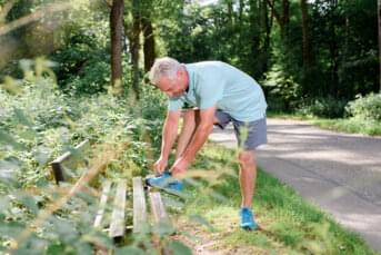 Mann bindet sich die Schuhe im Park