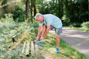 Mann bindet sich die Schuhe im Park