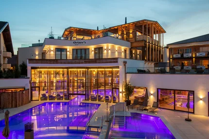 Luxurious Resort with Pool Ein luxuriöses Resort mit einem Außenpool, der neonblau beleuchtet ist. Die Architektur ist modern mit großen Fenstern, die den Blick auf den Pool und die Loungemöbel im Freien ermöglichen. Das Gebäude hat Holzstrukturen und ist sanft beleuchtet.