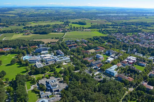 Luftaufnahme der Stadtlandschaft Eine Luftaufnahme einer Stadtlandschaft zeigt Gebäude, Straßen und grüne Felder unter blauen Himmel.
