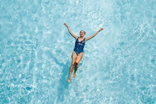 Frau im Wasser Eine Frau schwebt entspannt im blauen Wasser eines Schwimmbeckens.